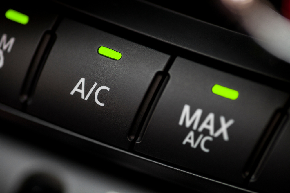 a/c repair, auto repair in York, PA at Quality Service Center. Illuminated close-up of a car’s A/C and MAX A/C buttons with green indicator lights showing the system is turned on.