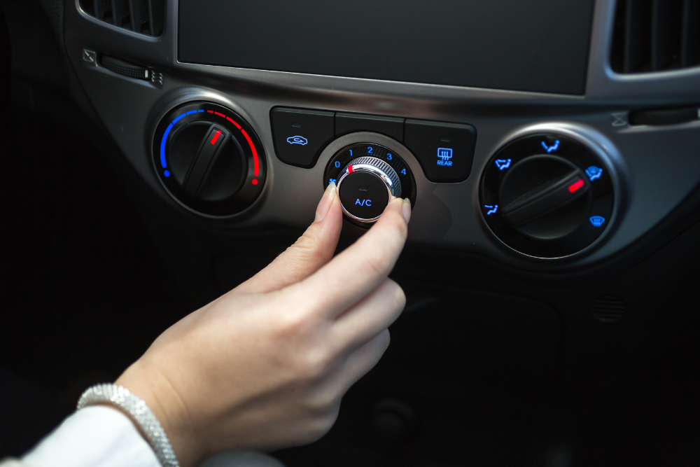 car a/c tips, auto repair in York, PA at Quality Service Center. Hand turning the A/C dial on a car’s climate control panel to adjust air conditioning settings.