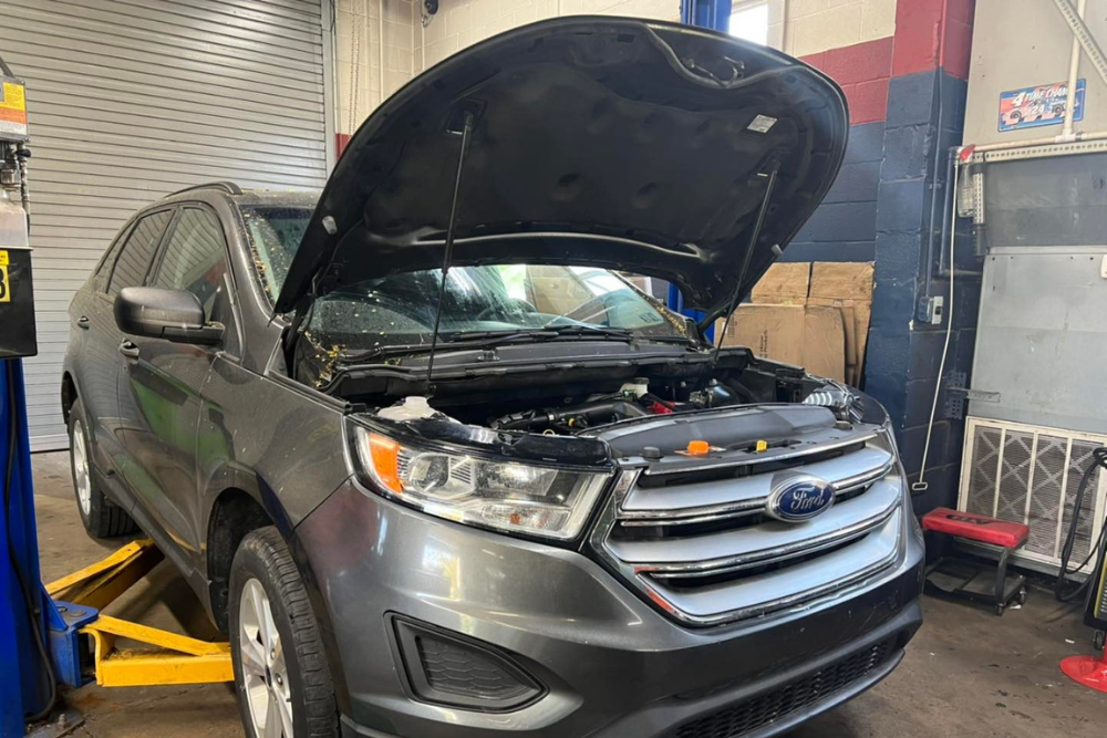 BG Maintenance Services in York, PA by Quality Service Center. Ford SUV with the hood open in an auto repair shop during seasonal maintenance service to prepare for fall and winter.