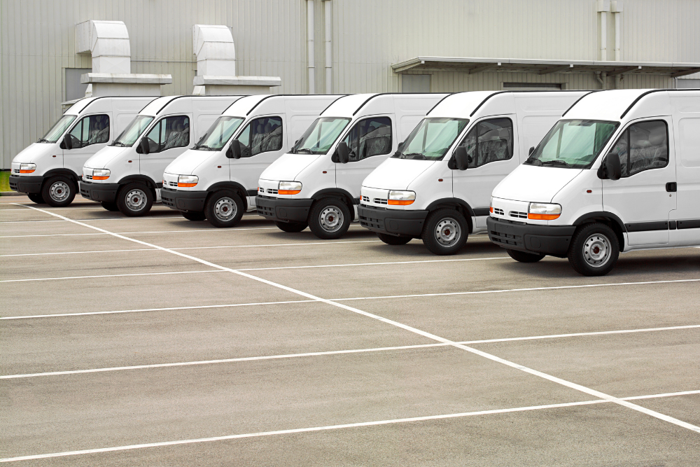 Fleet Maintenance in York, PA by Quality Service Center. A row of identical white cargo vans parked side by side in a large industrial parking lot.